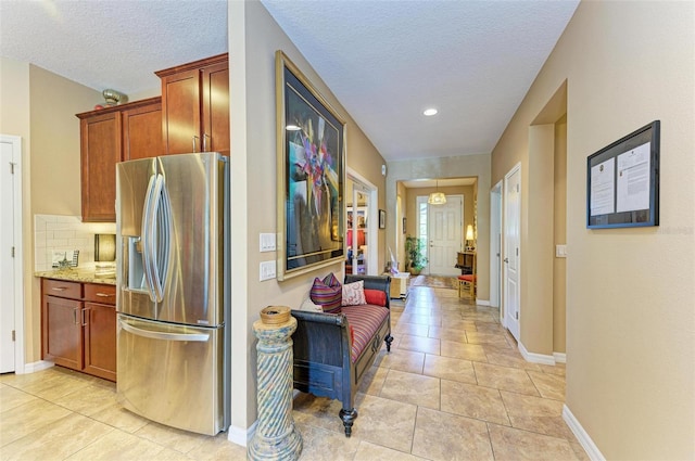 corridor featuring a textured ceiling and light tile patterned floors