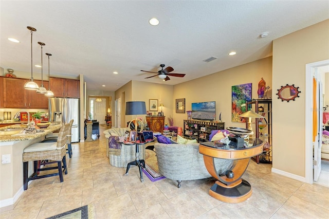 living room featuring ceiling fan, sink, and a textured ceiling