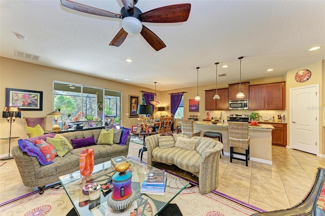 living room with light tile patterned floors, a textured ceiling, sink, and ceiling fan