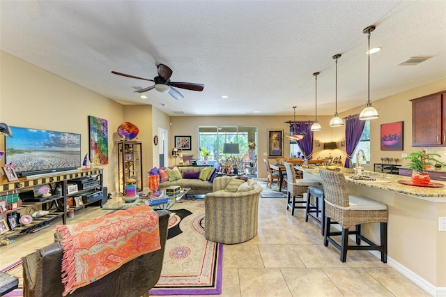 tiled living room featuring sink, a textured ceiling, and ceiling fan