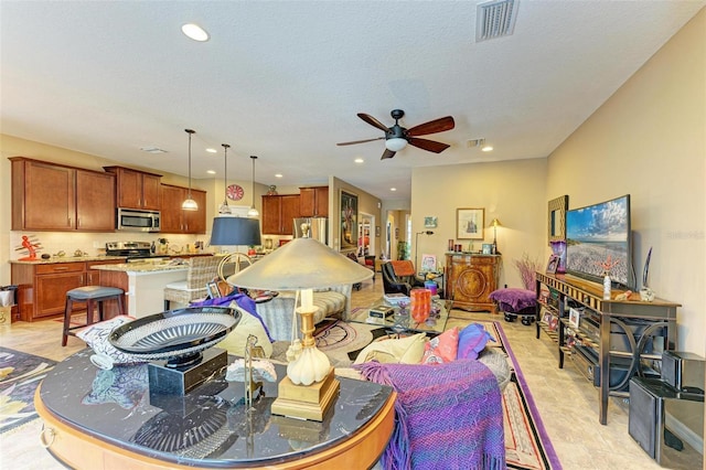 living room featuring ceiling fan and a textured ceiling