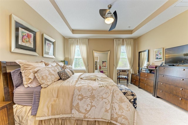 carpeted bedroom featuring a tray ceiling, a textured ceiling, and ceiling fan