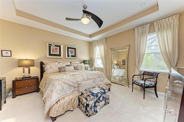 carpeted bedroom featuring a raised ceiling and ceiling fan