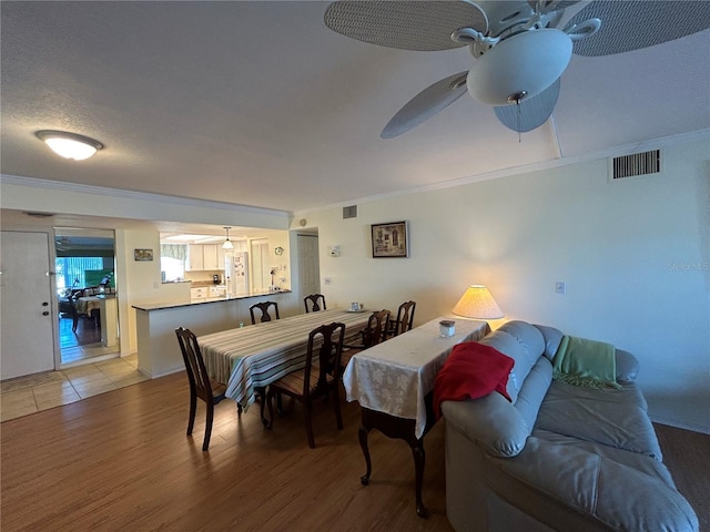 dining area with a textured ceiling, ceiling fan, crown molding, and hardwood / wood-style floors