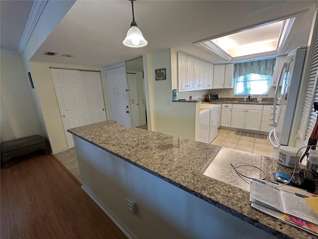 kitchen featuring light wood-type flooring, hanging light fixtures, ornamental molding, white cabinets, and sink