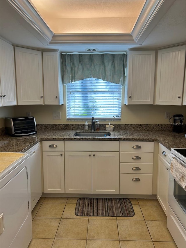 kitchen with washer / dryer, white cabinets, and sink