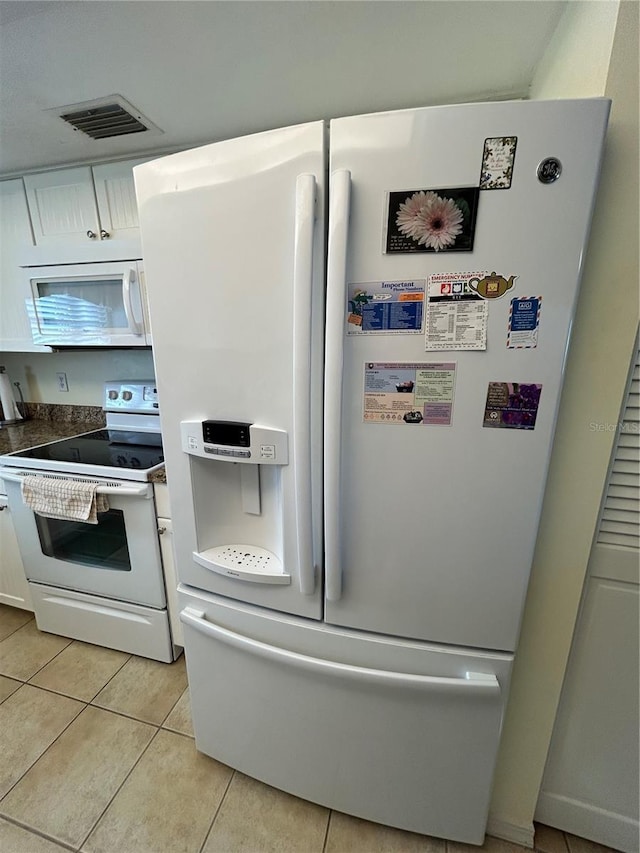 kitchen featuring light tile patterned flooring, white cabinets, and white appliances