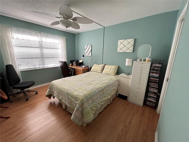 bedroom featuring ceiling fan, light wood-type flooring, and a textured ceiling