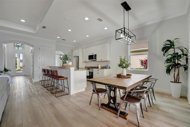 dining space with light wood-type flooring, a chandelier, and ornamental molding