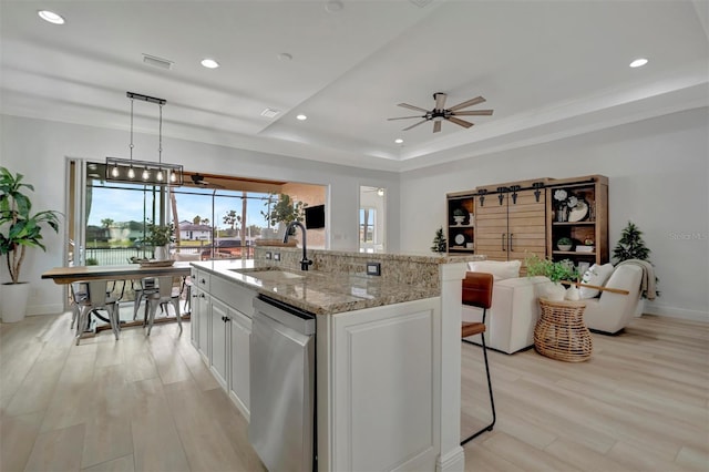 kitchen featuring white cabinetry, an island with sink, hanging light fixtures, stainless steel dishwasher, and sink