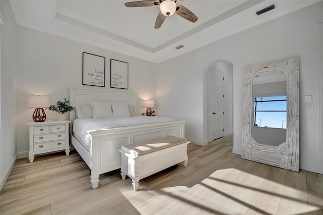 bedroom featuring light wood-type flooring, ceiling fan, and a tray ceiling