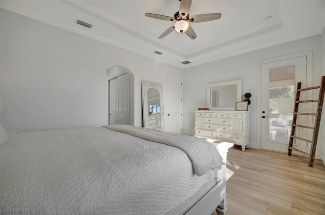 bedroom featuring ceiling fan, light hardwood / wood-style floors, crown molding, and a raised ceiling