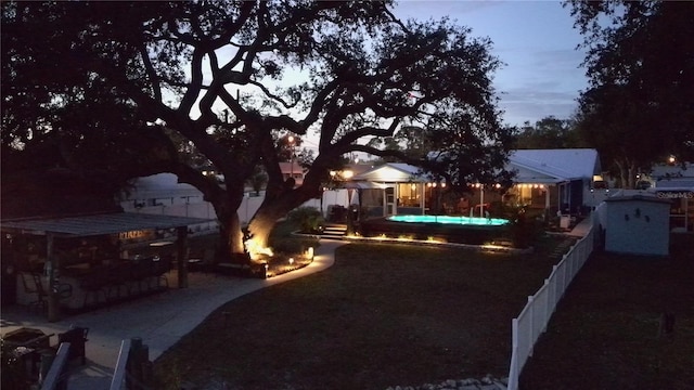 yard at dusk featuring a fenced in pool