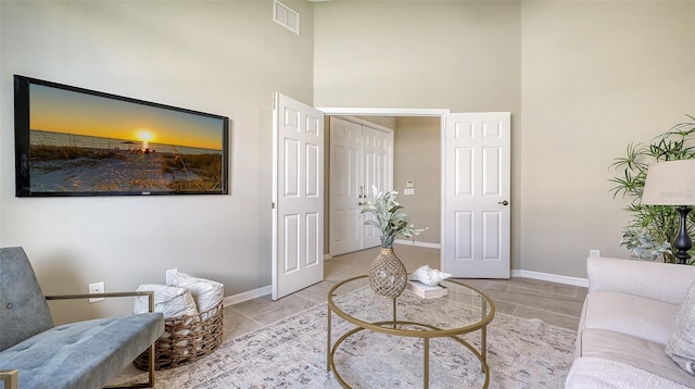 sitting room featuring a towering ceiling and light tile patterned floors