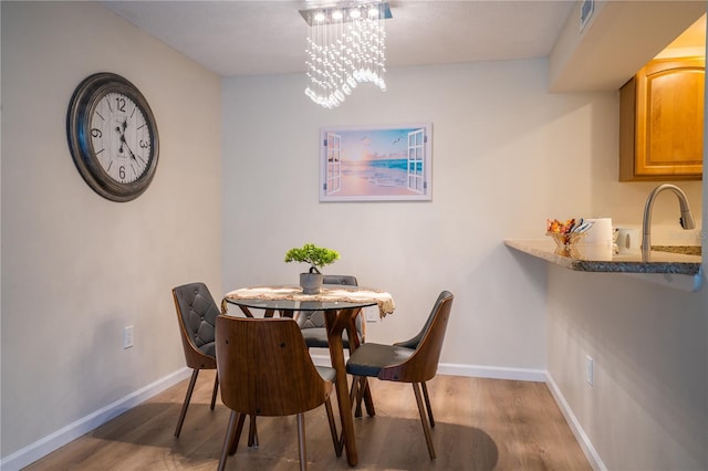 dining space featuring sink, dark hardwood / wood-style flooring, and a chandelier