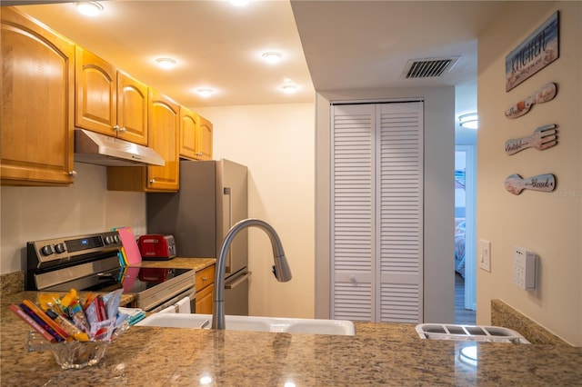 kitchen featuring stainless steel appliances, light stone counters, and sink