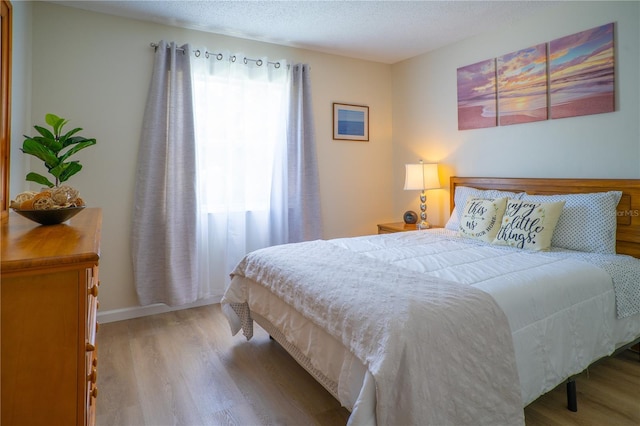 bedroom featuring a textured ceiling and light hardwood / wood-style flooring