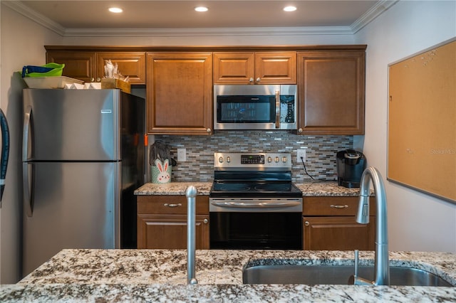 kitchen with light stone countertops, sink, backsplash, and appliances with stainless steel finishes