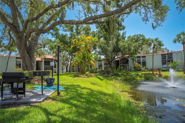 view of property's community with a lawn and a water view