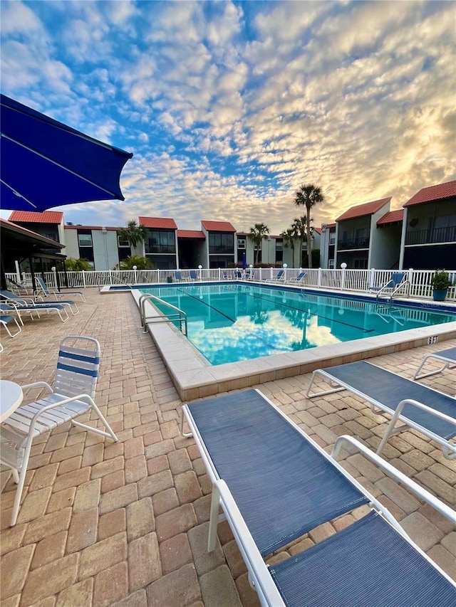 pool at dusk featuring a patio