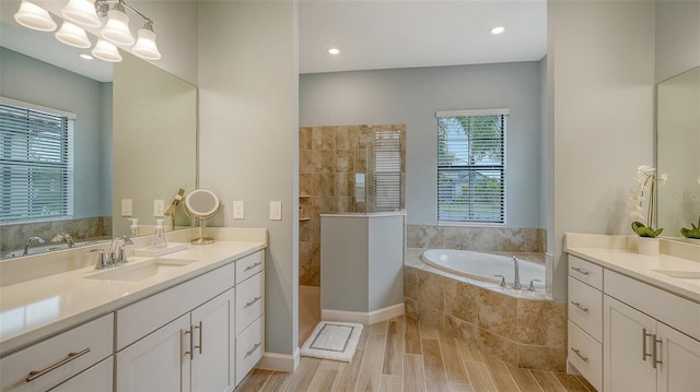 bathroom with plus walk in shower, a healthy amount of sunlight, and vanity