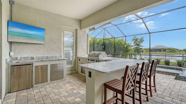 view of patio featuring a water view, a bar, grilling area, and area for grilling