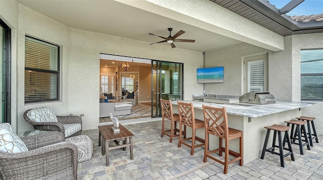 view of patio with grilling area, a bar, ceiling fan, an outdoor kitchen, and an outdoor living space