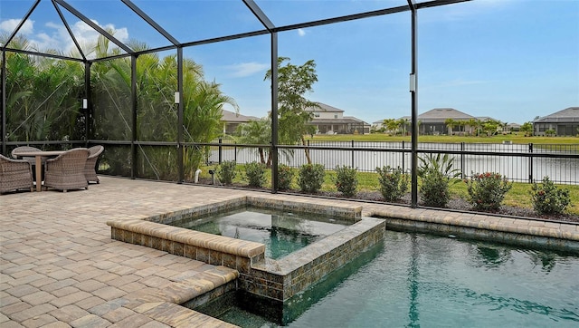 view of pool featuring glass enclosure, a water view, an in ground hot tub, and a patio