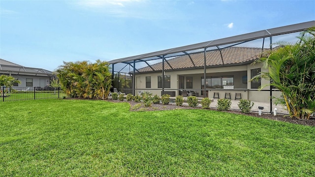 rear view of house with a yard and glass enclosure