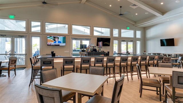 dining space with ceiling fan, high vaulted ceiling, beamed ceiling, and light hardwood / wood-style flooring