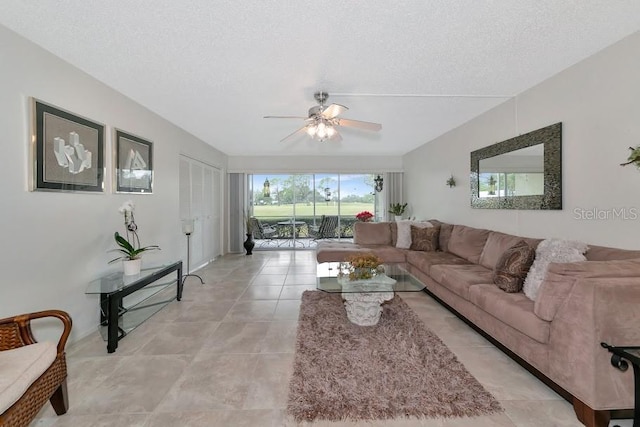 living room featuring a ceiling fan, light tile patterned flooring, and a textured ceiling