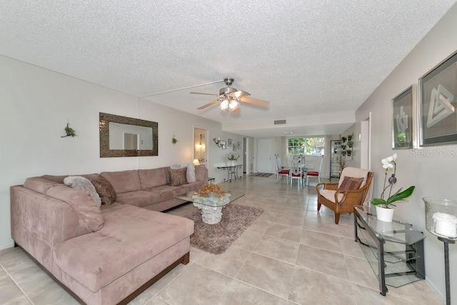 living area featuring light tile patterned floors, ceiling fan, visible vents, and a textured ceiling