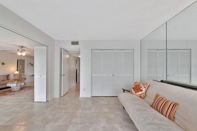 living area with a textured ceiling, light tile patterned floors, and visible vents