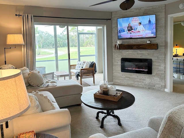 living room featuring ceiling fan, carpet floors, and a stone fireplace