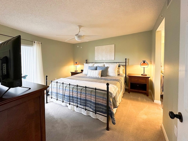 bedroom with ceiling fan, light carpet, and a textured ceiling