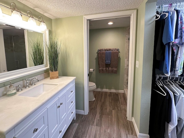 bathroom featuring hardwood / wood-style floors, toilet, vanity, and a textured ceiling