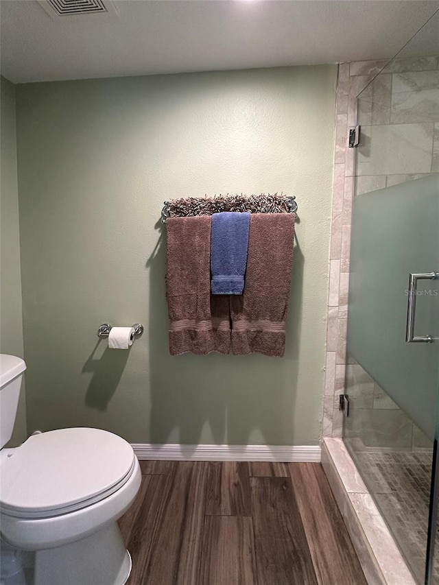 bathroom with toilet, a shower with door, and hardwood / wood-style flooring