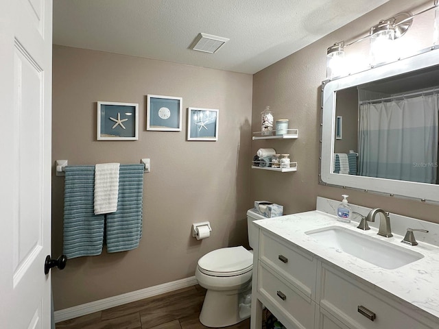 bathroom with toilet, vanity, and a textured ceiling