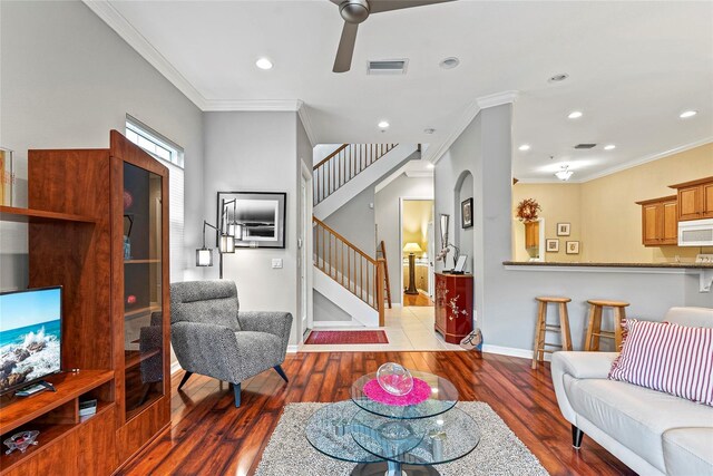 living room featuring ceiling fan, hardwood / wood-style flooring, and crown molding