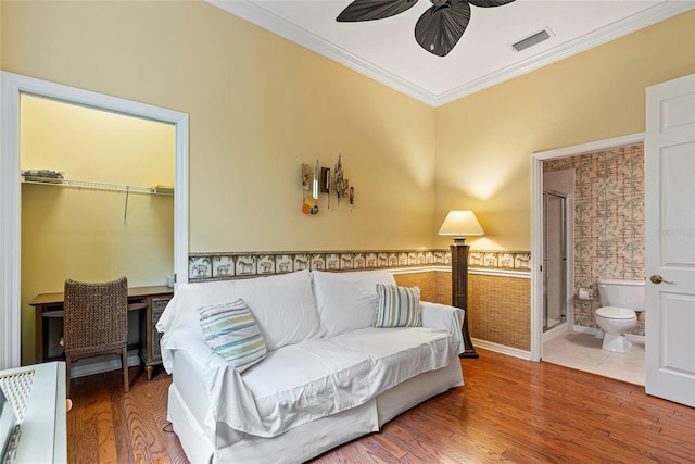 bedroom featuring ceiling fan, ornamental molding, wood-type flooring, and ensuite bath