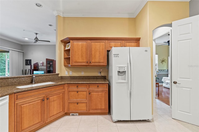 kitchen featuring sink, white appliances, ornamental molding, light tile patterned floors, and dark stone counters