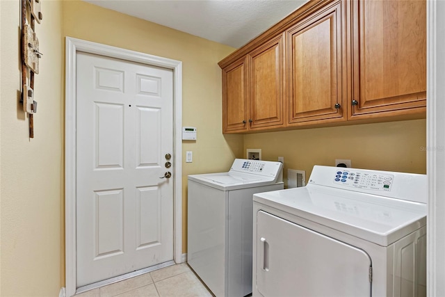 laundry room with light tile patterned flooring, cabinets, and washer and dryer