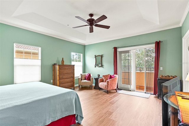 bedroom featuring ceiling fan, access to exterior, light hardwood / wood-style flooring, and a raised ceiling