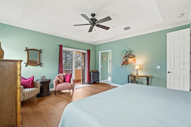 bedroom featuring ceiling fan, access to exterior, hardwood / wood-style floors, and a raised ceiling