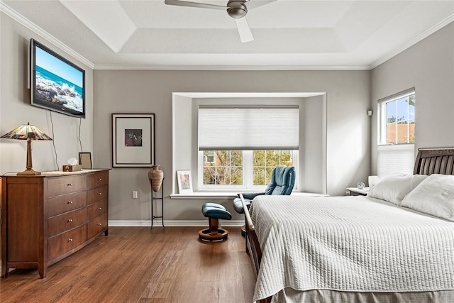 bedroom with ceiling fan, hardwood / wood-style floors, a tray ceiling, and crown molding