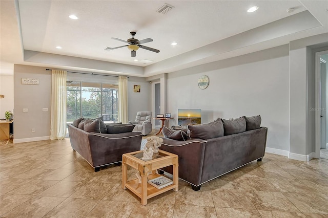 living room featuring a tray ceiling and ceiling fan