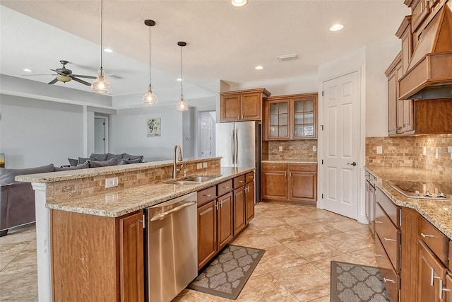 kitchen with pendant lighting, sink, appliances with stainless steel finishes, tasteful backsplash, and custom range hood