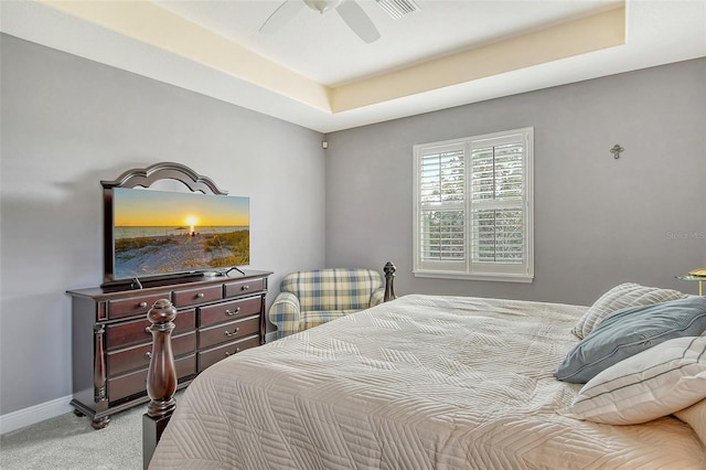 carpeted bedroom with ceiling fan and a tray ceiling