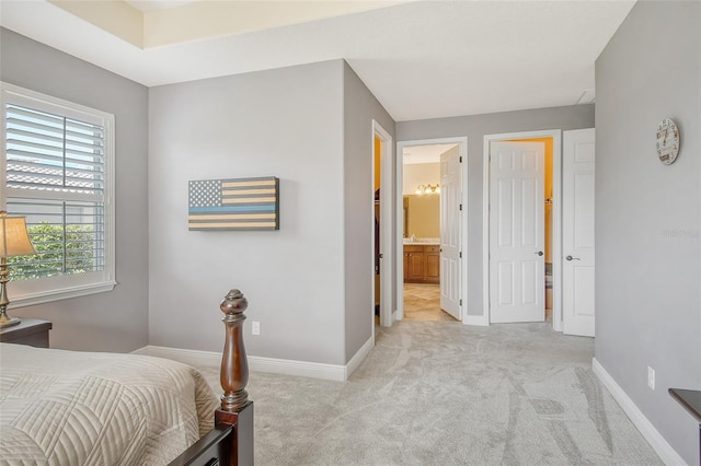 bedroom featuring ensuite bathroom and light colored carpet