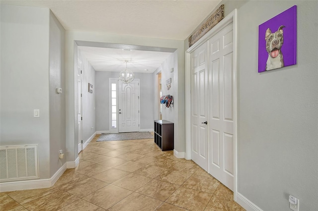 foyer entrance with an inviting chandelier and light tile patterned floors